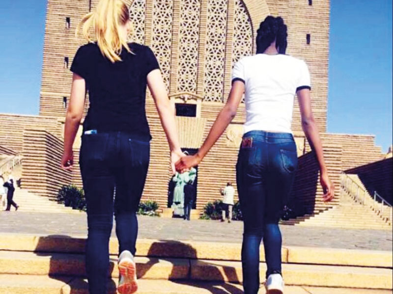 Austauschschülerin geht Hand in Hand mit afrikanischer Freundin eine Treppe hinauf