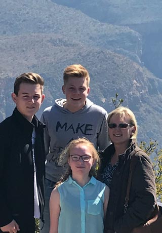 Austauschschüler mit Gastfamilie vor Hügellandschaft in Südafrika