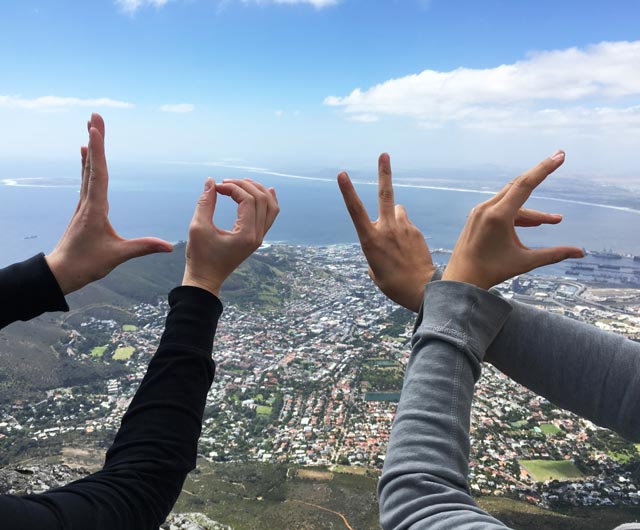 Zwei Schüler formen mit ihren Händen das Wort Love. Im Hintergrund ist eine afrikanische Stadt zu sehen.