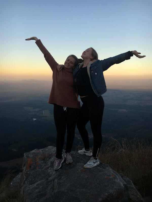 Zwei glückliche Mädchen an einer Klippe bei Sonnenuntergang