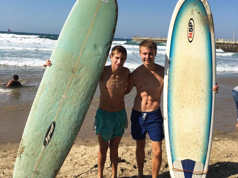 Zwei fröhliche Surfer am Strand mit Surfbrettern