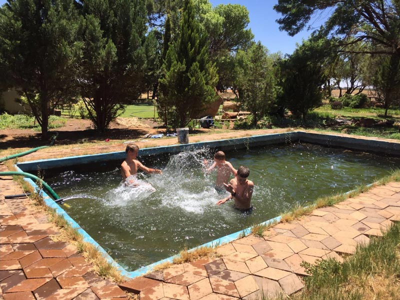 Drei Schüler haben Spaß im Pool bei sommerlichen Temperaturen